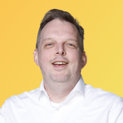 Foto van Mindcollege trainer Mark Kupers in een wit overhemd op een gele achtergrond