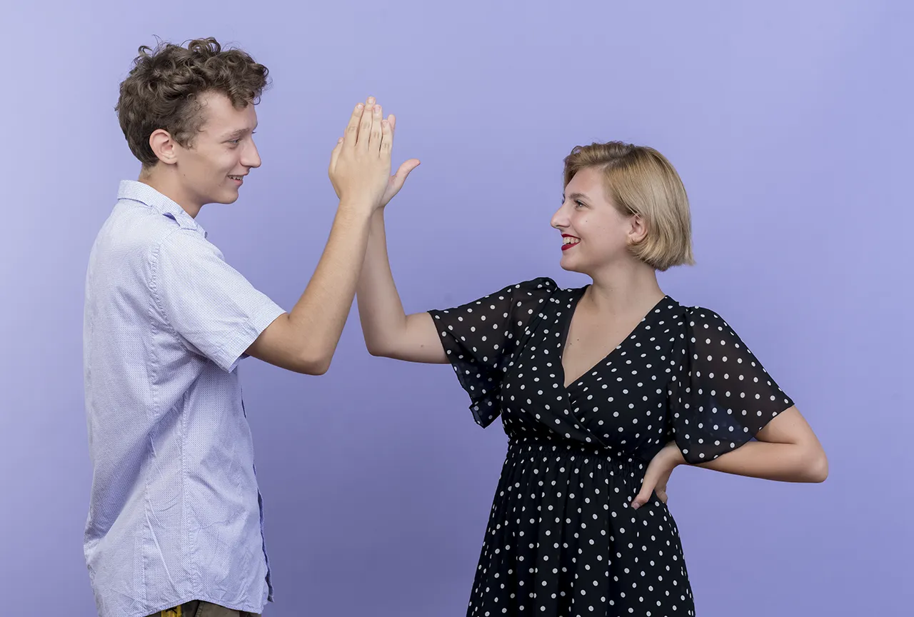 Jongen en meisje geven elkaar high-five tegen paarse achtergrond