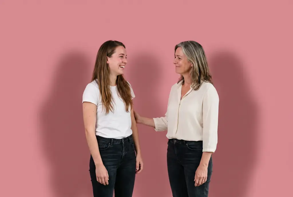 Twee vrouwen, moeder en dochter, lachen elkaar toe tijdens een familieopstelling